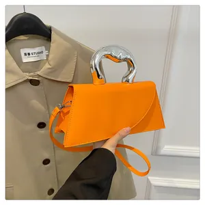 Nahaufnahme der leuchtend orangefarbenen Trapez-Handtasche mit silbernem Metallgriff