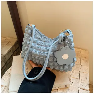 Detailed view of light blue bubble textured fabric bag with floral charm and metal rings
