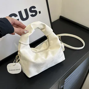 Detail of off-white velvet handbag featuring knotted handle and gold metal zipper
