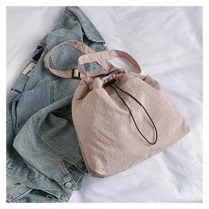 Detail of light pink drawstring bucket bag with adjustable strap on denim background