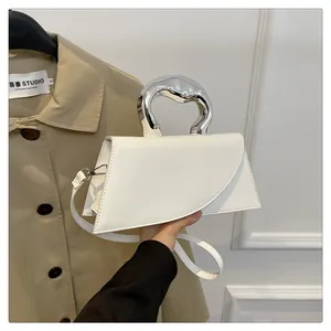 Detail einer weißen Lederhandtasche mit flüssig wirkendem Silbergriff und Umschlagklappe
