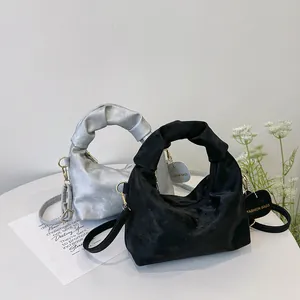 Detailed shot of velvet handbags with ruched handles and gold fashion tags in black and silver