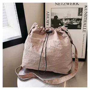 Detail view of pink wrinkled nylon shoulder bag with drawstring closure and large front pocket