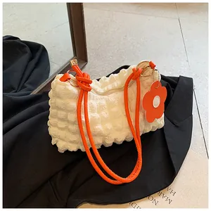 Close-up of white bubble texture fabric with orange tubular handle and flower charm
