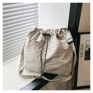 Macro detail of beige nylon crossbody bag featuring drawstring closure and adjustable strap