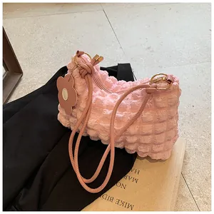 Detail of light pink bubble texture shoulder bag with floral charm and gold metal rings