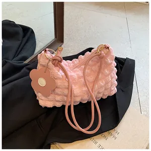 Detail of pink bubble textured pleated shoulder bag with floral charm on black fabric