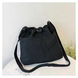 Detail of black drawstring crossbody bag showing fabric texture and adjustable closure
