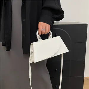 Minimalistische weiße Ledertasche mit asymmetrischer Klappe und silbernem Bogengriff