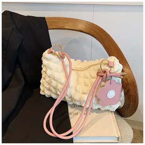 Detail of white bubble texture fabric bag with pink straps and flower charm