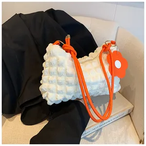 Detail of white popcorn texture fabric bag with orange rope strap and flower charm