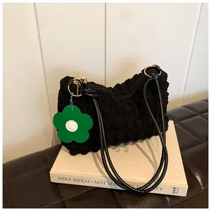 Detail of black bubble texture fabric on a shoulder bag with a green flower charm