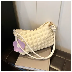 Detail of white bubble texture fabric shoulder bag with purple flower charm and gold rings