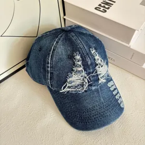 Dettaglio del cappellino in denim blu scuro effetto consumato con bordi sfrangiati e fori