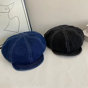 Detail of vintage denim newsboy caps showing white contrast stitching and thick texture