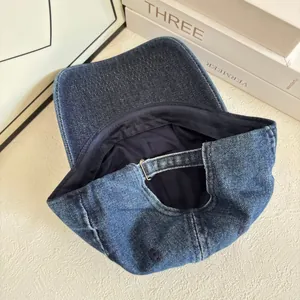 Dettaglio del cappellino in denim blu navy con cinturino in metallo e cuciture interne
