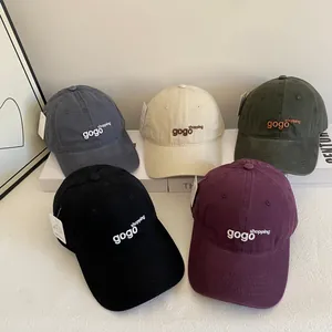 Close-up of five washed cotton baseball caps with gogo shopping embroidery in assorted colors