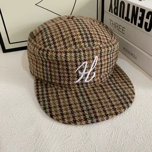 Détail de la casquette plate vintage avec motif pied-de-poule et broderie lettre H