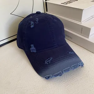 Detailed view of the distressed edges and frayed holes on a dark blue vintage baseball cap
