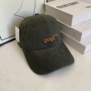 Detailed macro view of military green cotton baseball cap featuring orange embroidery and tags