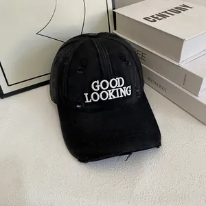 Close-up of white 'GOOD LOOKING' embroidery on a black distressed vintage baseball cap