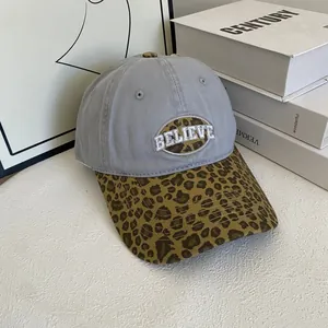 Close-up of leopard print patchwork and white BELIEVE embroidery on gray baseball cap