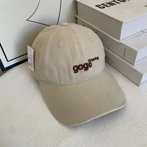 Close-up of beige cotton baseball cap with gogo shopping embroidery and product tags