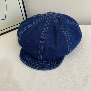 Close-up of navy denim newsboy cap featuring white contrast stitching and retro style
