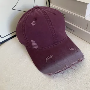 Detailed view of distressed burgundy cotton baseball cap with vintage frayed brim effects
