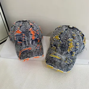 Distressed denim baseball cap with vintage wash and orange stitching on white stand