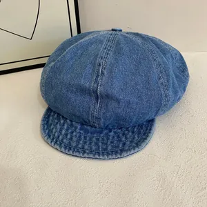 Detail view of washed blue denim newsboy cap with premium stitching and top button