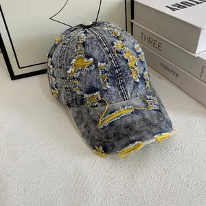 Close-up of distressed denim baseball cap showing yellow lining and torn details