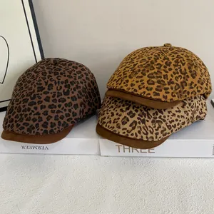 Three leopard print berets in different tones with stylish brown leather brims on display