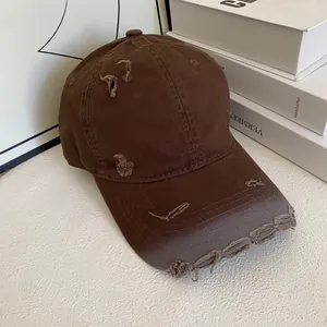 Detailed close-up of dark brown distressed baseball cap with ripped denim texture