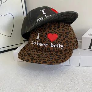 Detail von bestickten Baseballcaps mit Camouflage- und Leopardenmuster und lustigem Text