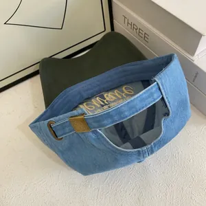 Detail of metal adjustment buckle and embroidery on light blue denim baseball cap