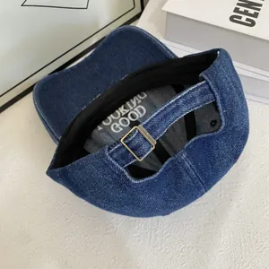 Detailed interior of a navy denim baseball cap with white 'LOOKING GOOD' embroidery inside