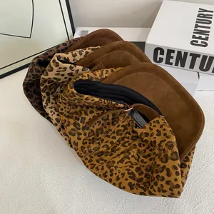 Flat lay of leopard print and brown faux suede baseball caps on a textured surface