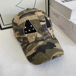 Camo baseball cap with silver rivets and distressed ripped details on a white table