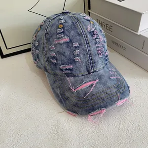 Close-up of distressed denim baseball cap with pink stitching and vintage torn details
