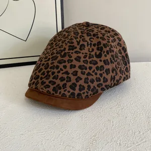 Close-up of leopard print newsboy cap featuring a brown faux suede brim and soft fabric