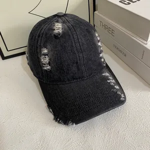 Détails d'une casquette en denim gris foncé délavé avec des finitions déchirées