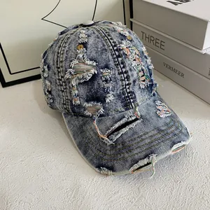 Close-up of distressed denim baseball cap showing torn details and colorful stitching
