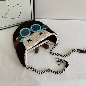 Detail of crochet aviator hat showing textured knit, goggles, and earflap braids