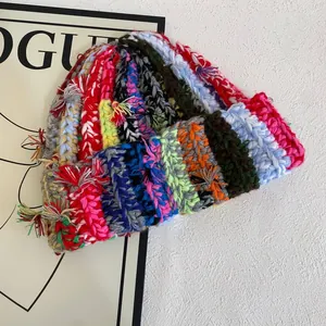 Handmade chunky knit beanie with vibrant colorful stripes and bohemian fringe details