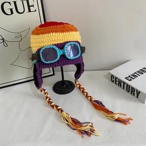 Detail of colorful knit aviator beanie with blue goggles and braided tassels