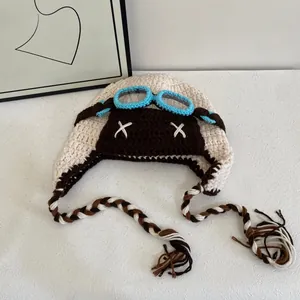 Detail of hand-knitted aviator hat with X-shaped stitching and tassel braided ties