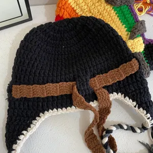 Detail of handmade crochet aviator beanie with braided tassels and boho knitting texture