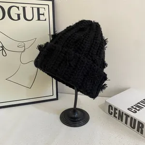 Detailed texture of black chunky knit beanie featuring frayed fringe accents and warm wool