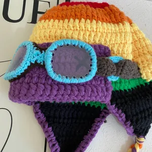 Detail of colorful rainbow knit pilot hat with blue crochet goggles and ear flaps